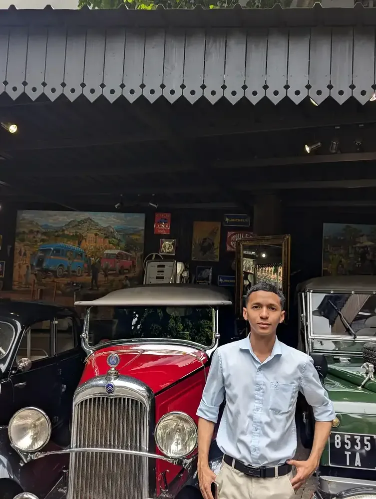 HT, founder of Madalo Travel and first Madalo Helper, photographed in Antananarivo with vintage cars and paintings of old Tana